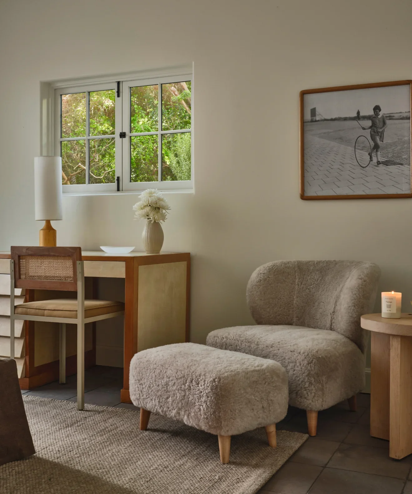 Living room with a sofa, ottoman, and a window with greenery outside